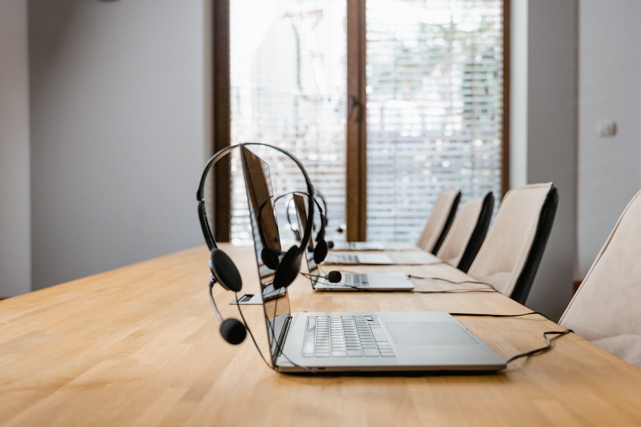 who-we-are Modern conference room with laptops and headsets lined up ready for a meeting.