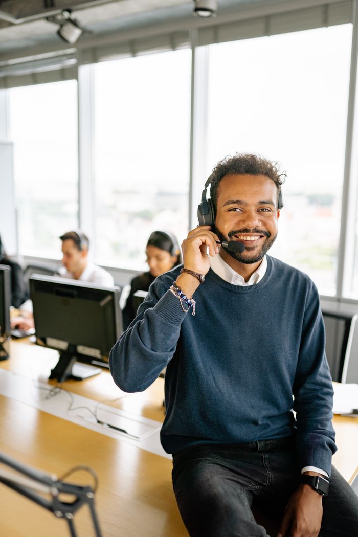 services-04 Happy man in headset sitting at desk in modern office, engaging in work.